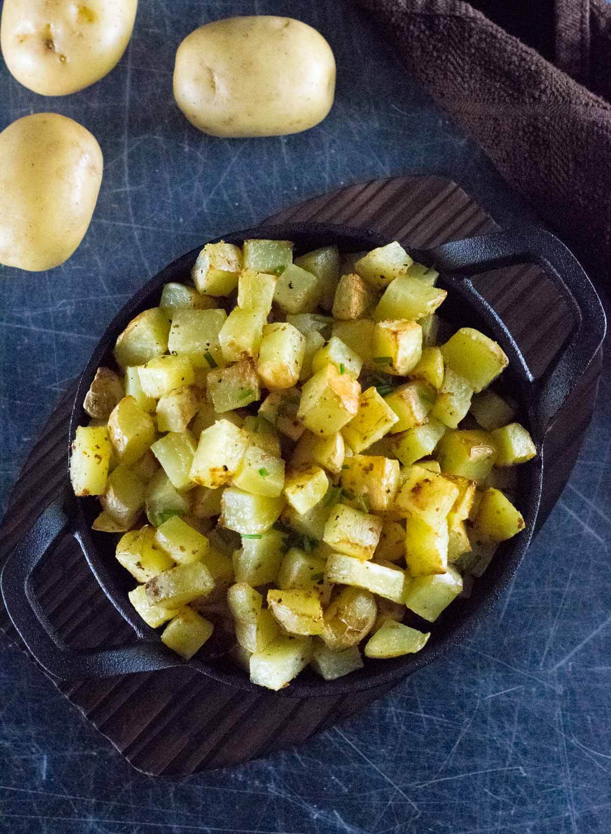 Easy breakfast potatoes in black dish viewed from above.