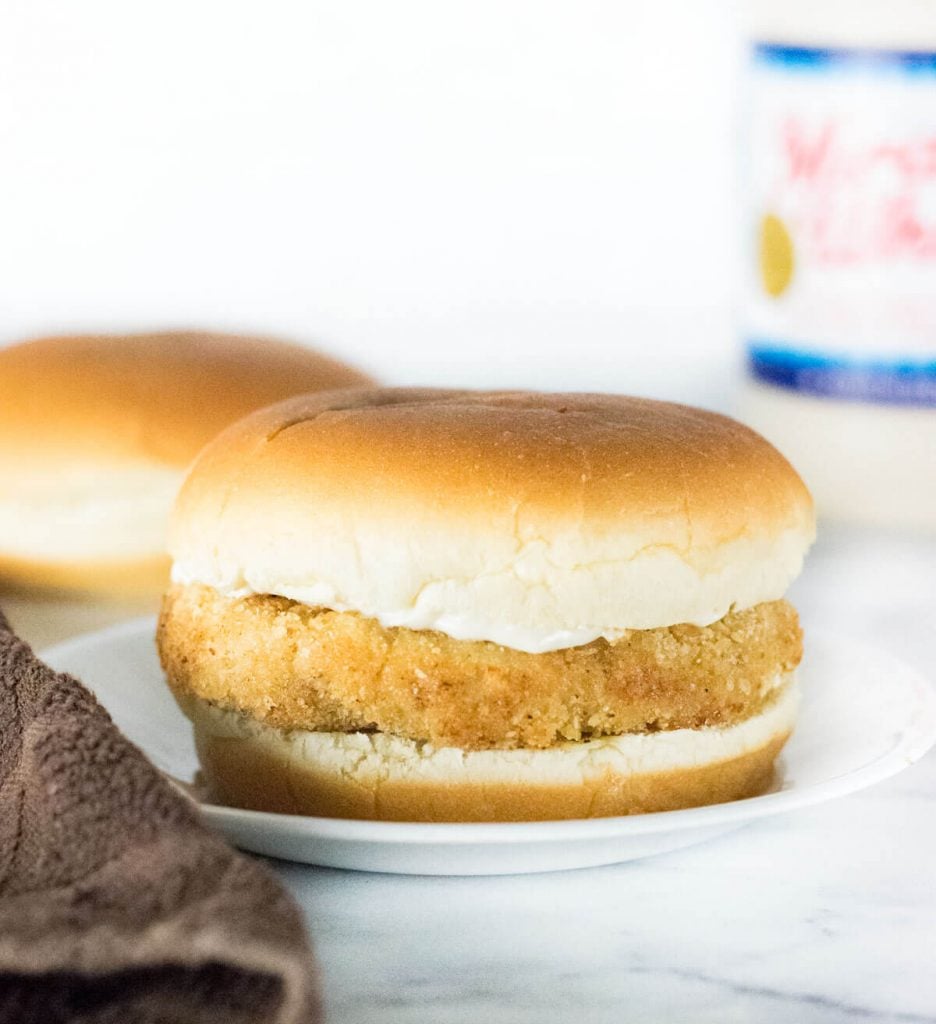 Homemade Chicken Patty on hamburger bun with jar of mayo behind.