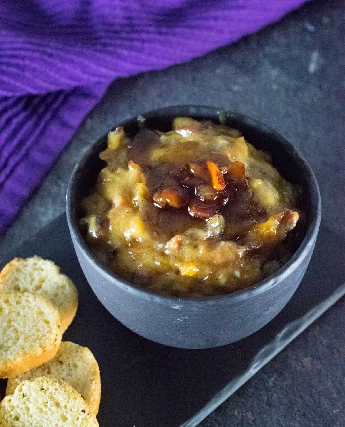 Bacon dip in a black bowl served with bagel chips