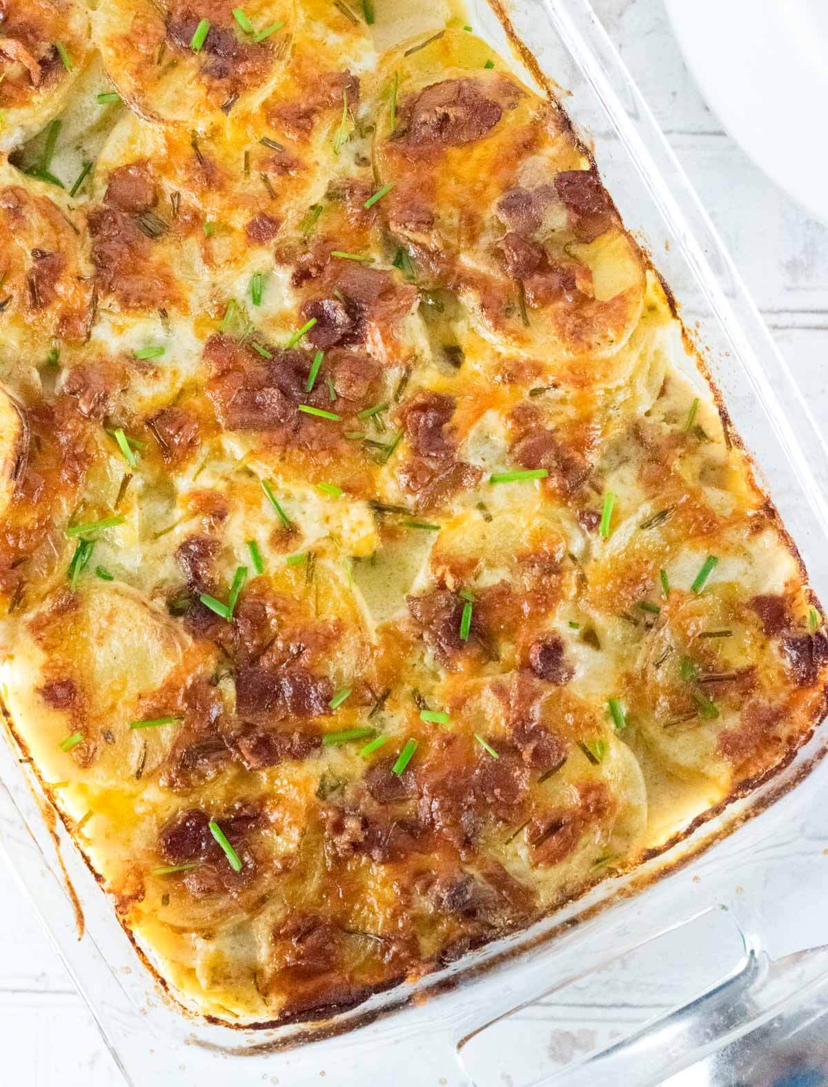 Loaded scalloped potatoes viewed in clear dish from above.