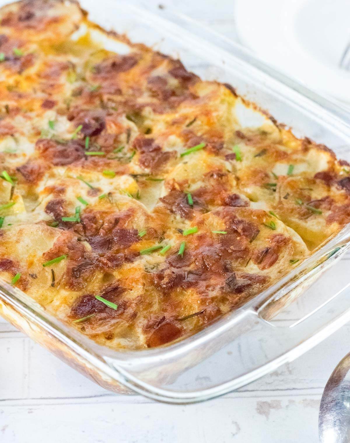 Scalloped potatoes with bacon in a pan topped with chives.