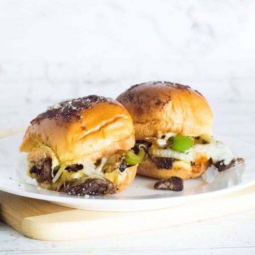 Squared image of two Philly cheesesteak sliders on plate.