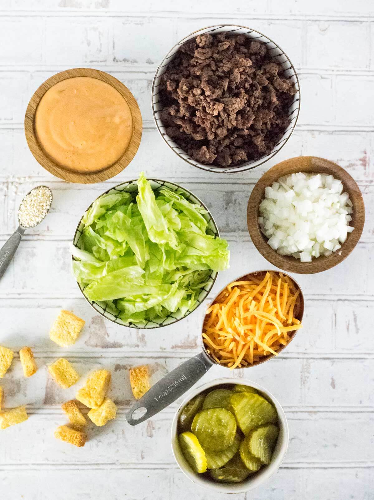 Big Mac Salad ingredients in separate dishes shown from above.