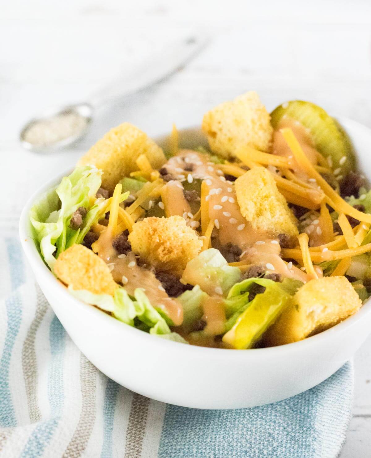 Big Mac Salad in white bowl sitting on kitchen towel.