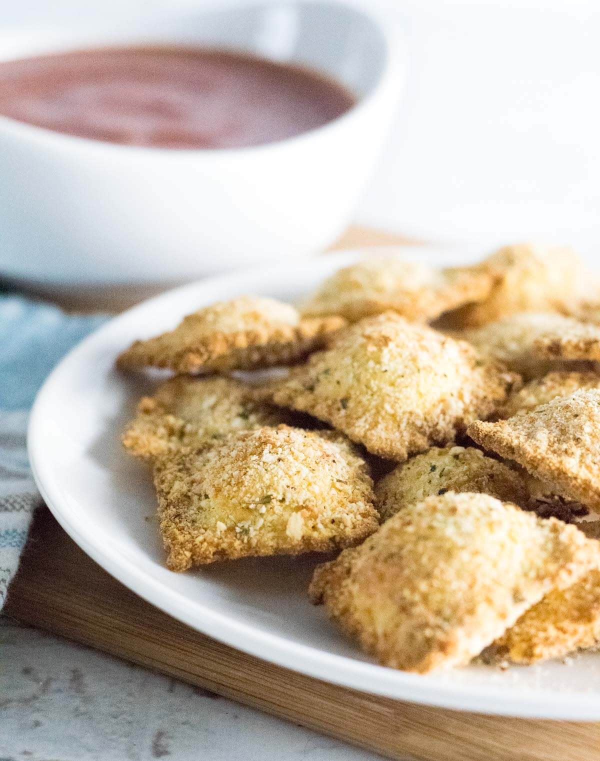 Closeup of toasted ravioli with marinara sauce in a white bowl.