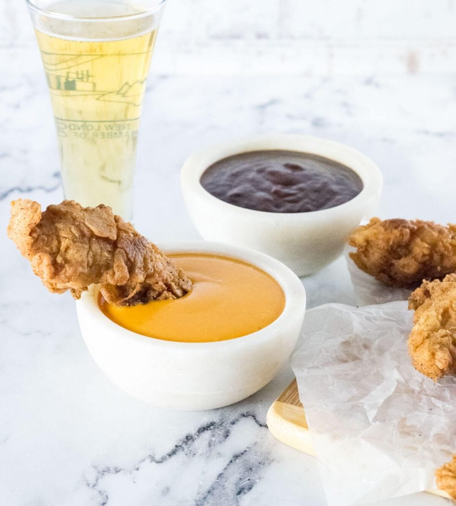 Chicken tenders in dipping sauce, showing BBQ and comeback sauce.