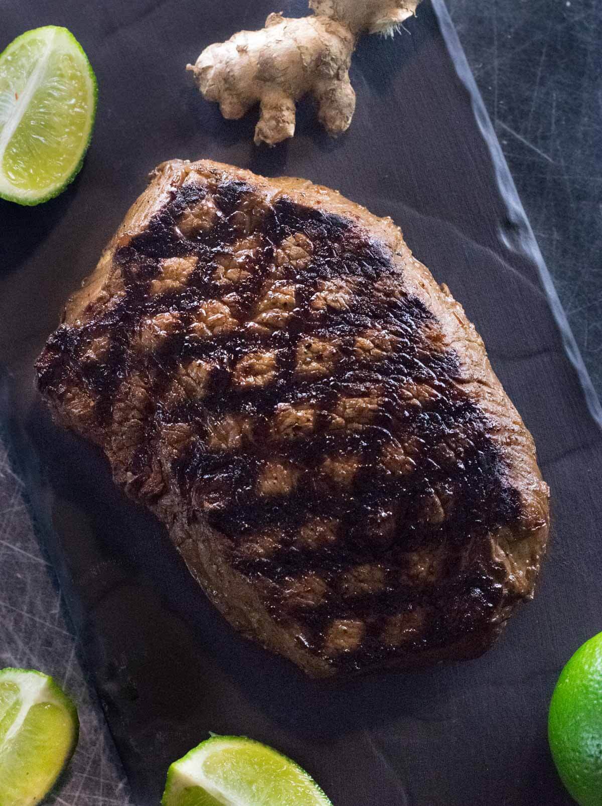 Asian marinated steak on a black tray.