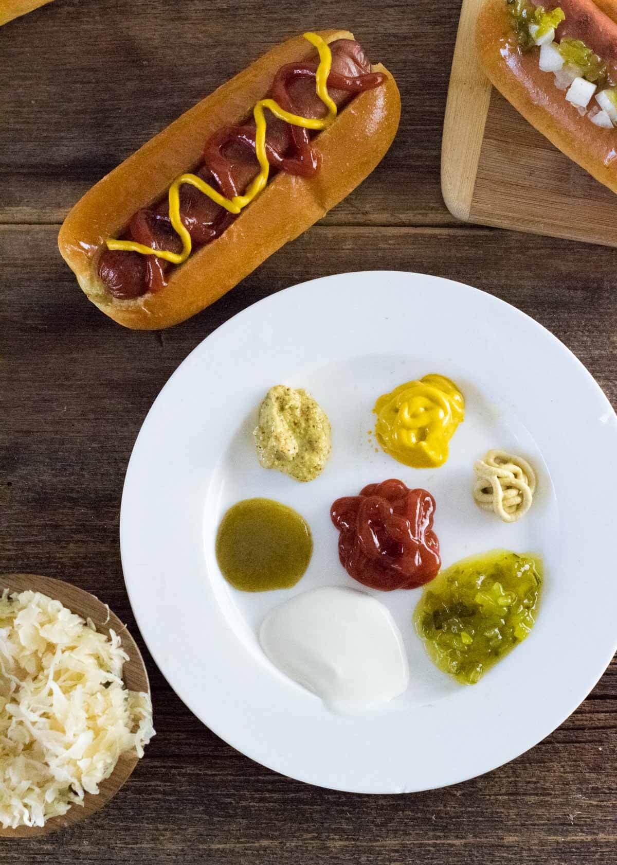 Hot dog condiments on a white plate.