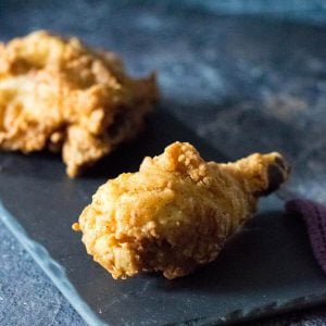 Broasted chicken on a black tray.