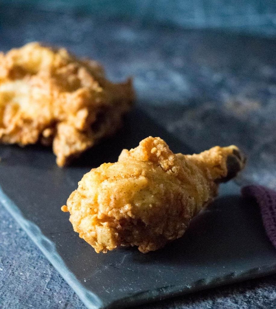 Broasted chicken on a black tray.