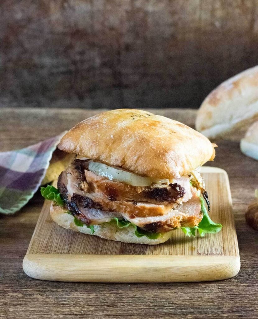 Grilled pork loin sandwich on cutting board.