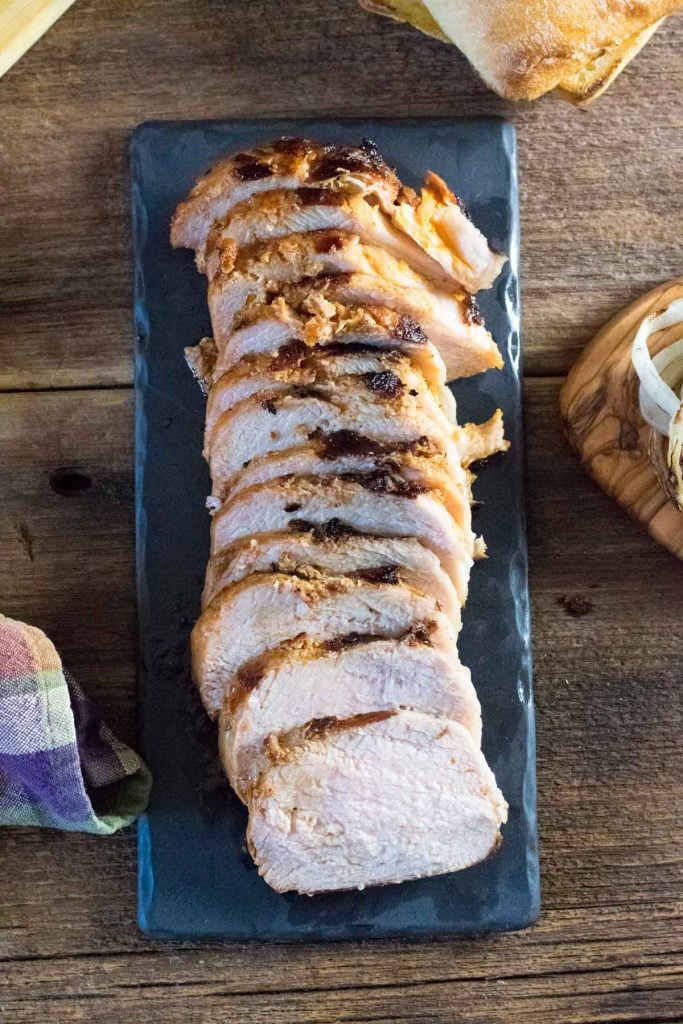 Grilled and sliced pork loin on black board.