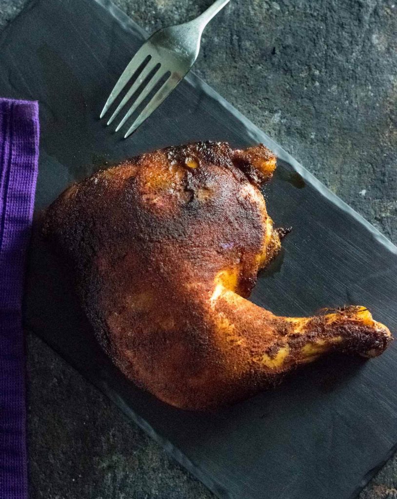 Smoked chicken quarters with fork.
