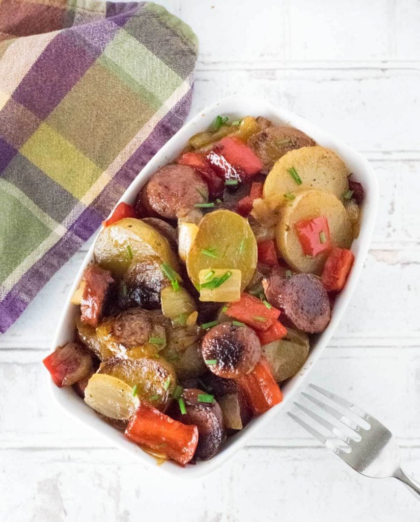 Smothered potatoes and sausage in white dish viewed from above.