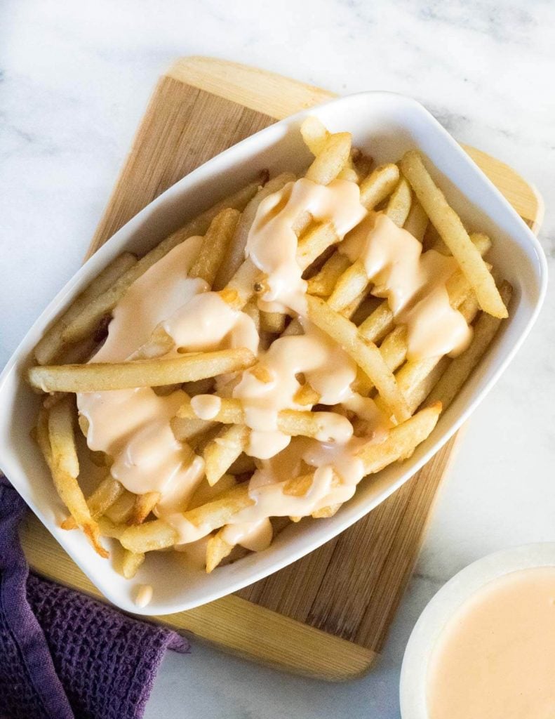 Cheese fries on wooden board.