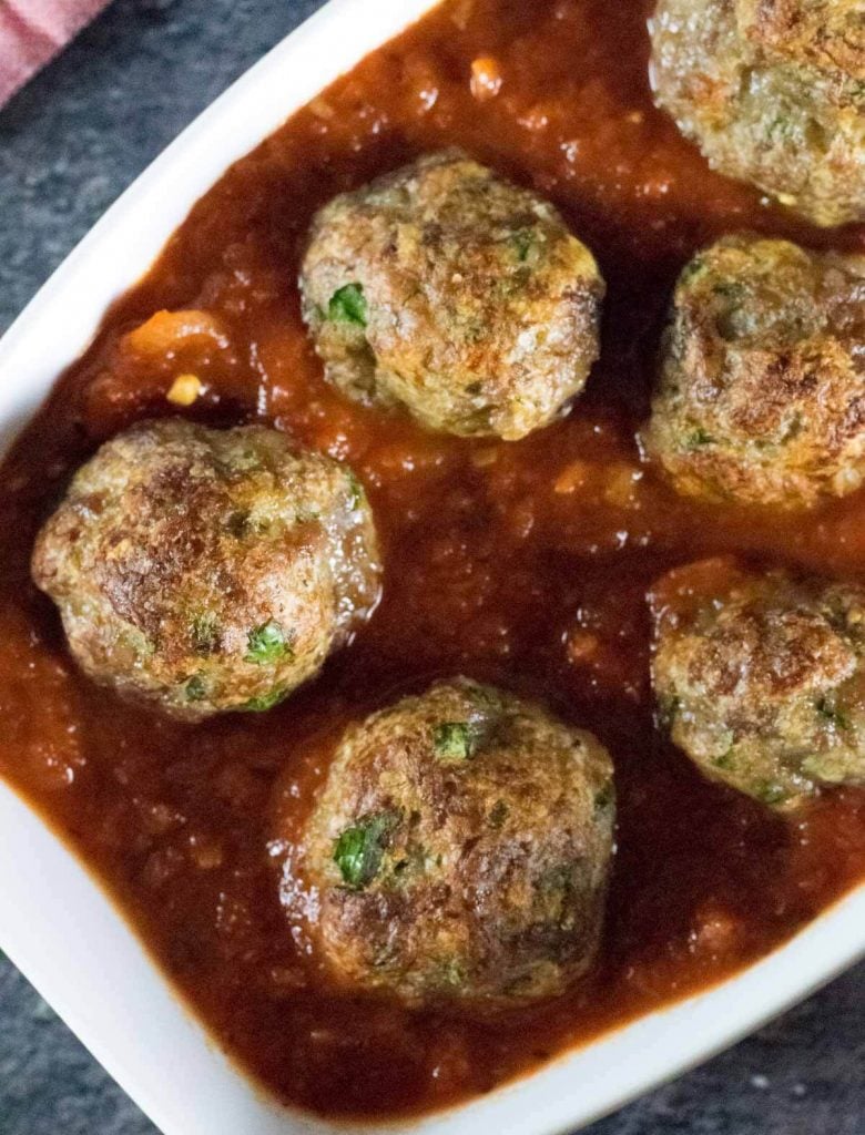 Italian sausage meatballs in sauce shown close up.