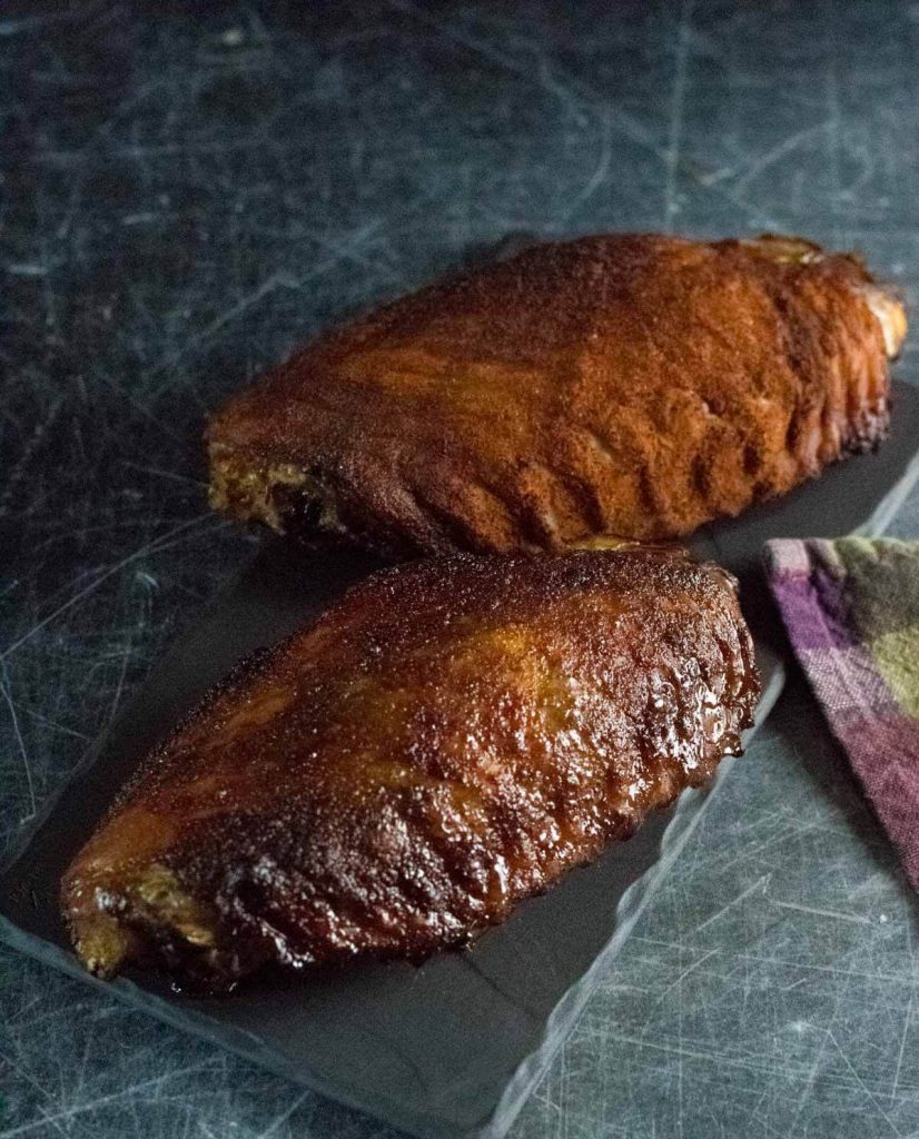 Smoked turkey wings on dark board.