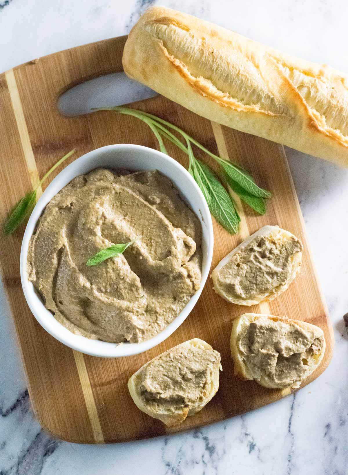 Beef liver pate with bread on cutting board.