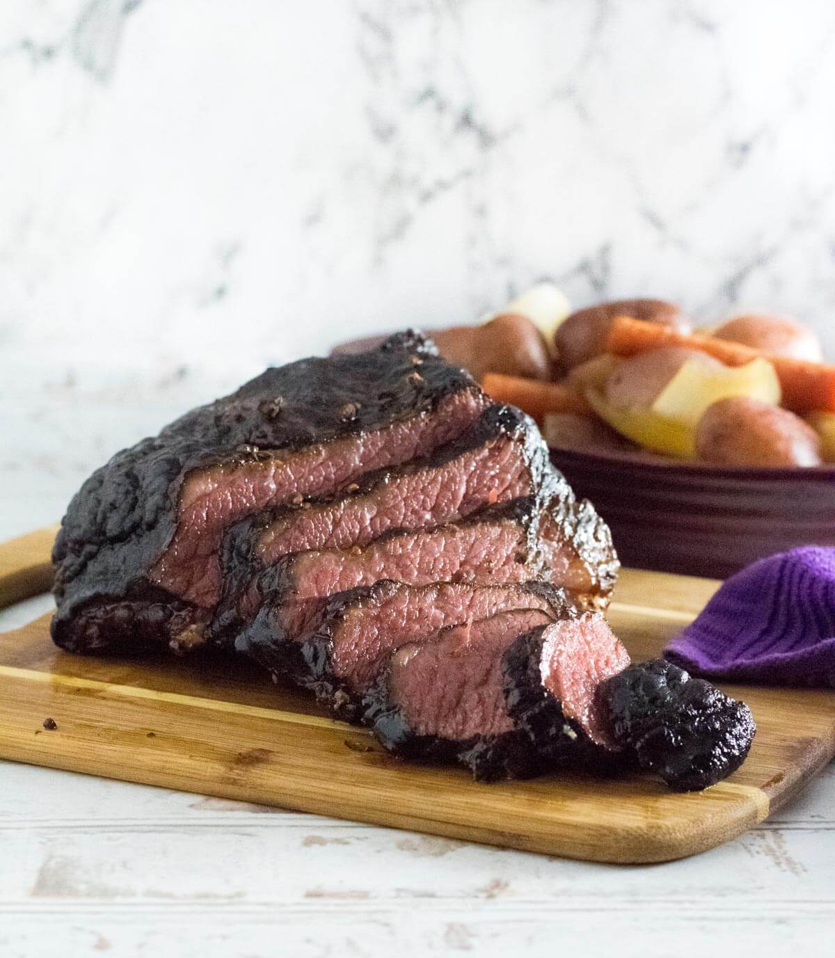 Tender smoked corned beef sliced on cutting board.