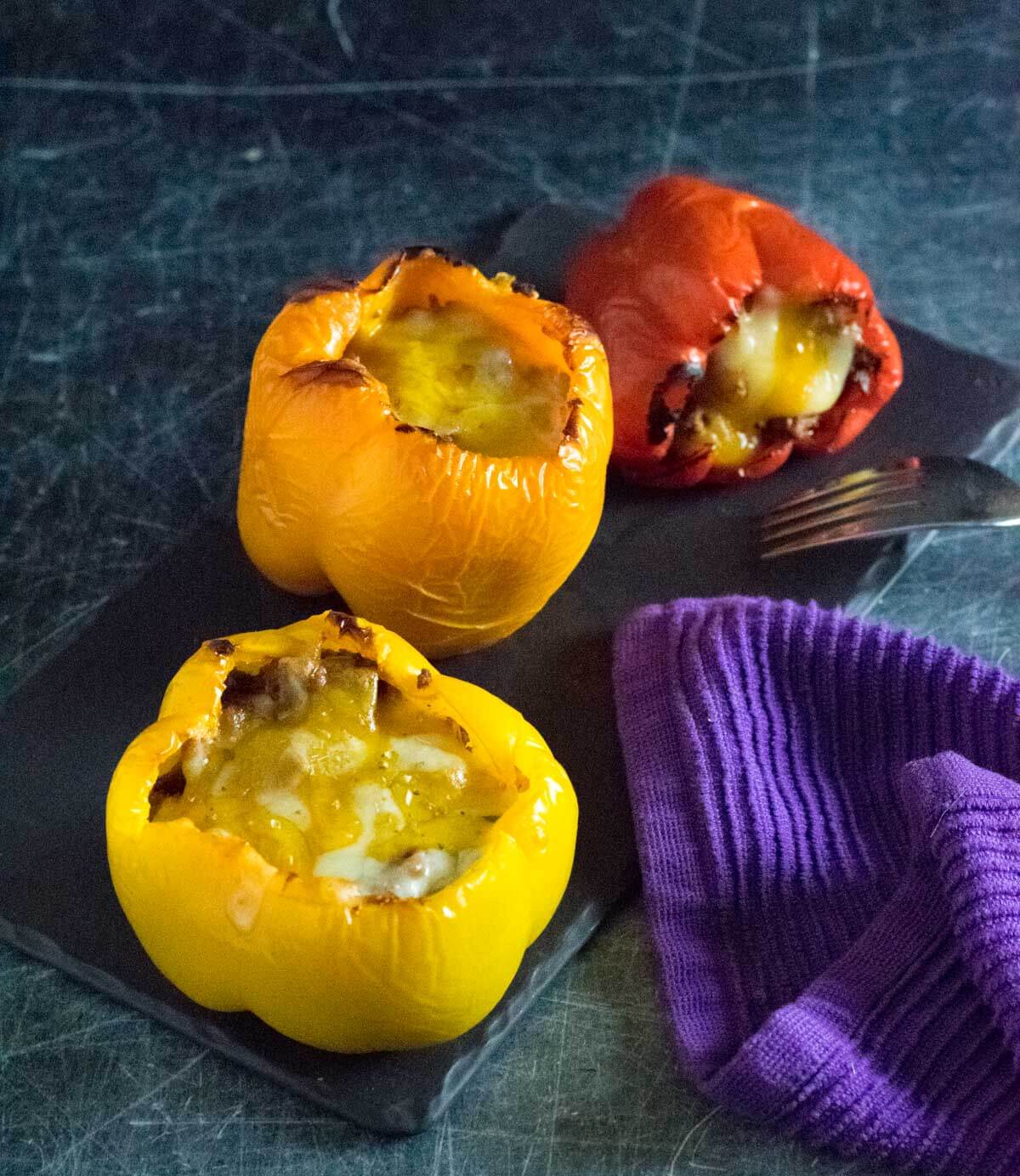 Stuffed bell peppers with beef on black tray.
