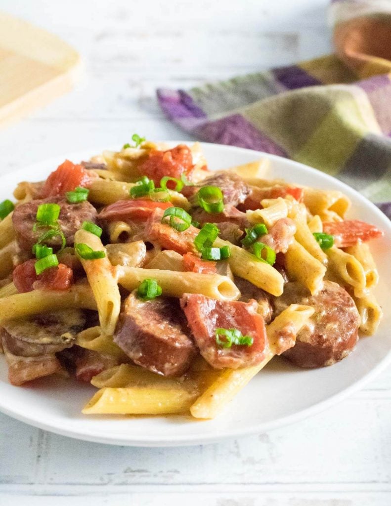 Andouille sausage pasta family dinner on white plate.