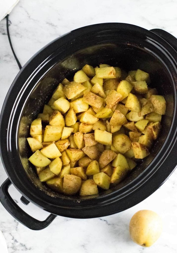 Raw potatoes in slow cooker with seasonings.