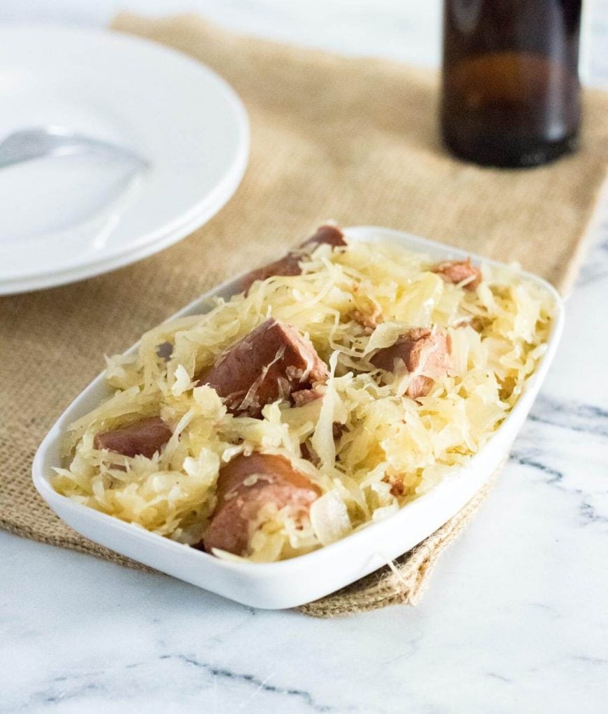 Crockpot sauerkraut and kielbasa in white dish.