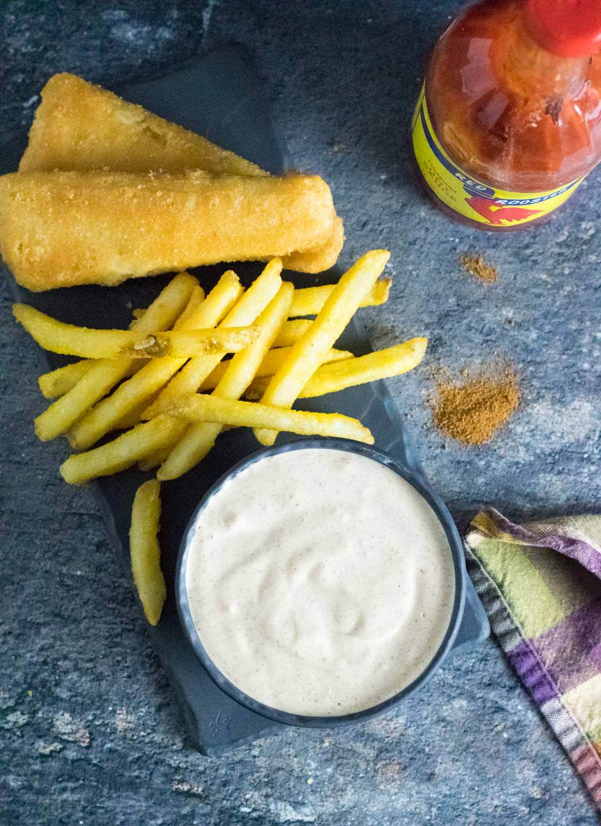 Cajun dipping sauce with Fried food and french fries.