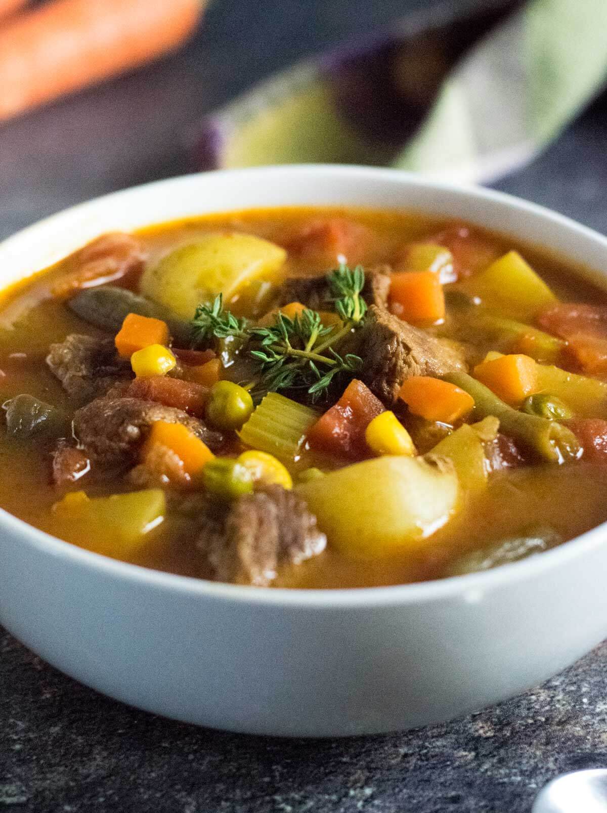 Serving vegetable beef soup in white bowl.