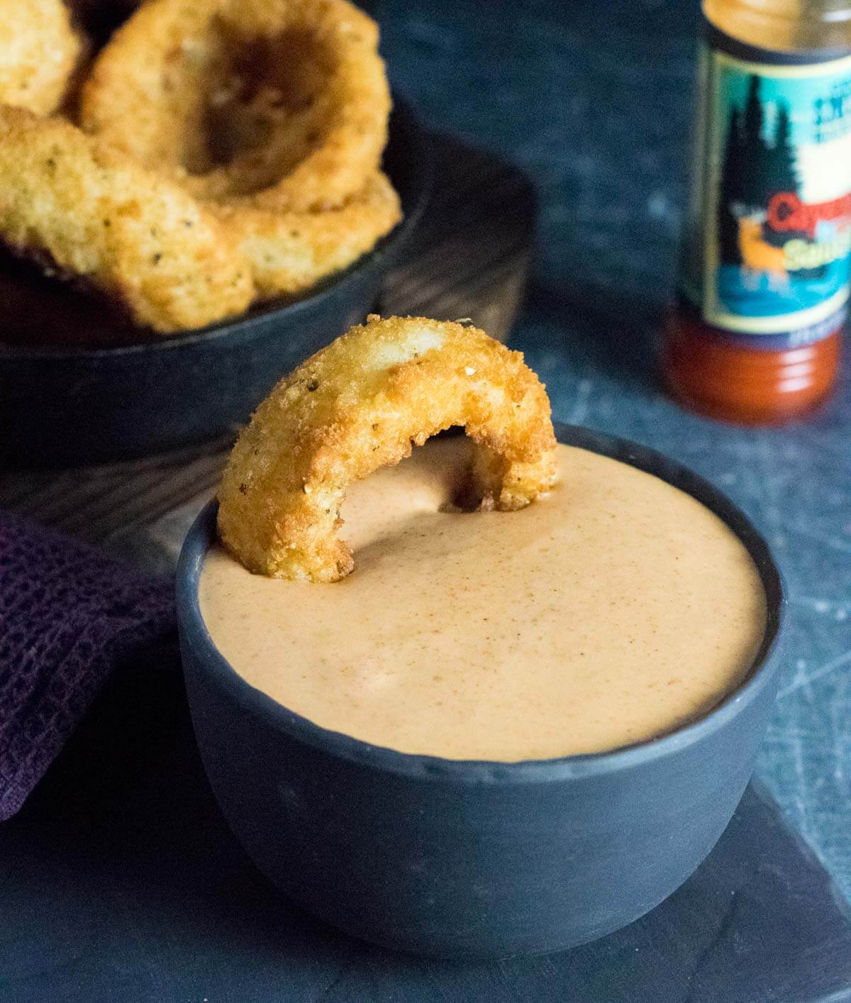 Dipping onion ring in spicy sauce.