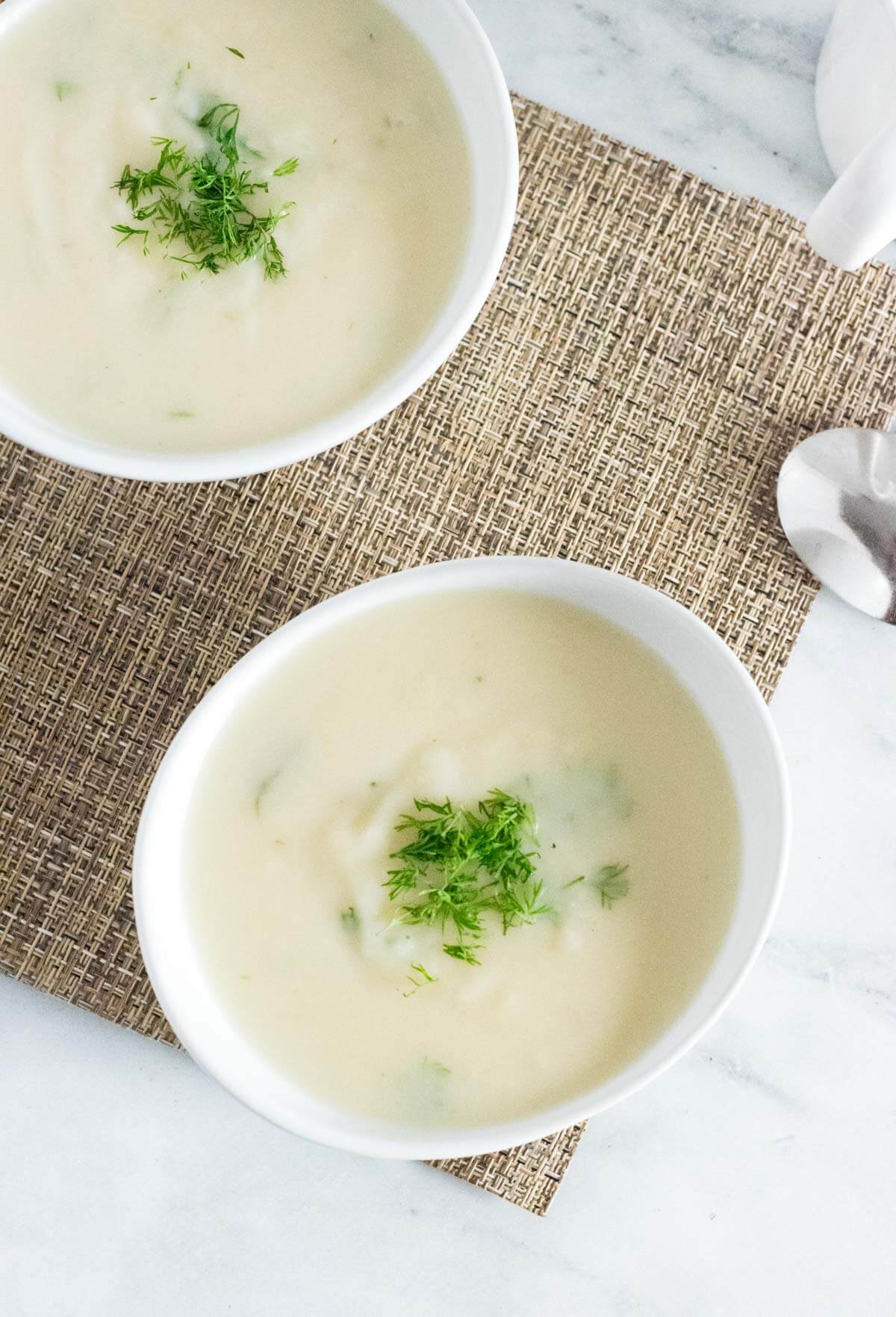 Two white bowls with potato soup.