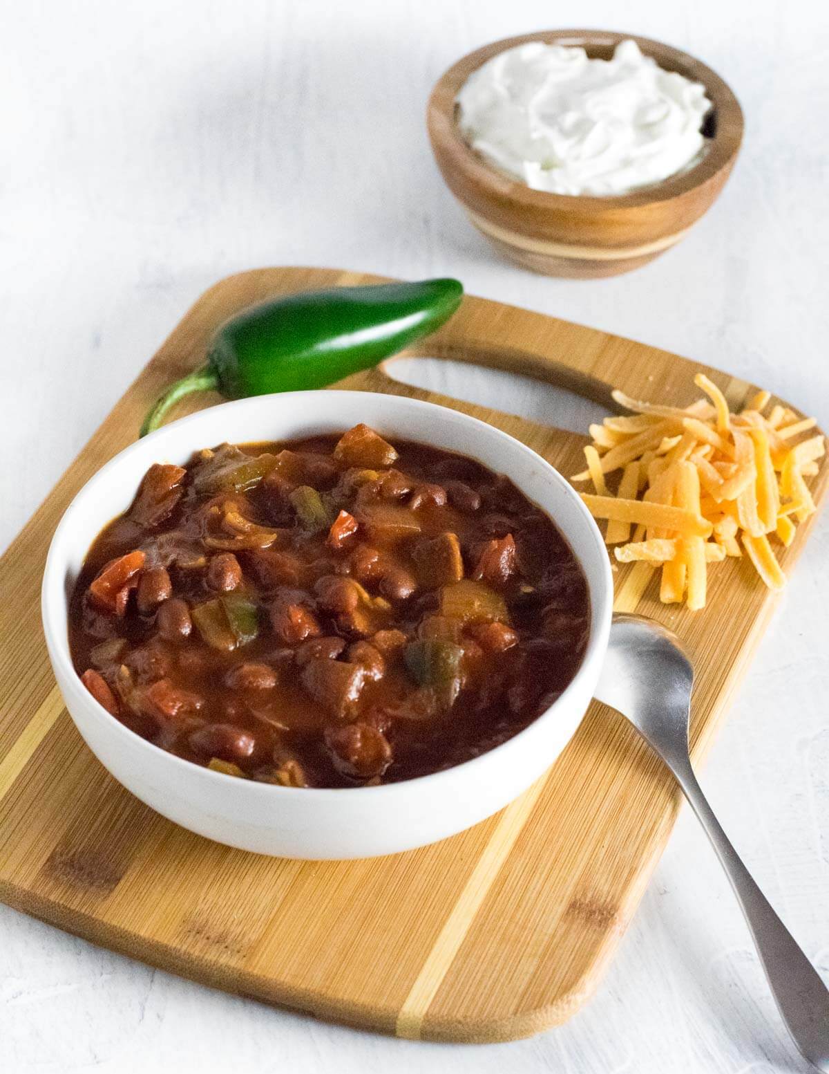 Serving BBQ brisket chili with toppings.