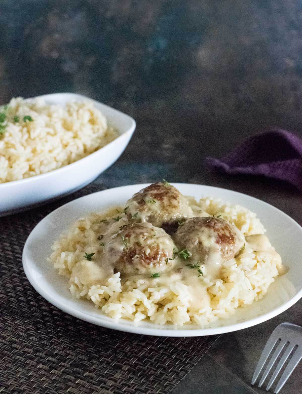 Serving meatballs and gravy over rice.